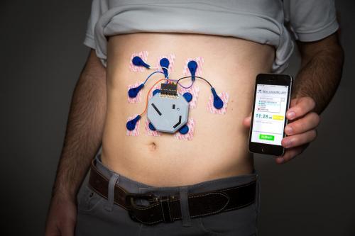 Device worn on bare stomach; hand holding phone with app